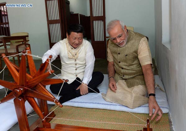 Chinese President Xi Jinping (L) rotates a spinning wheel that was once used by Mahatma Gandhi as he visits Gandhi